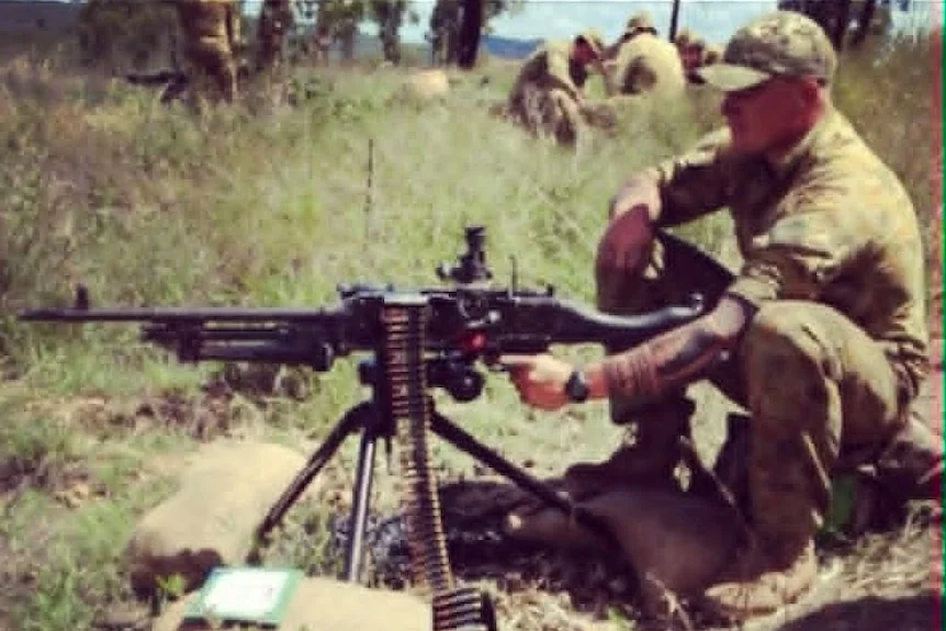 A man in army uniform at a machine gun.
