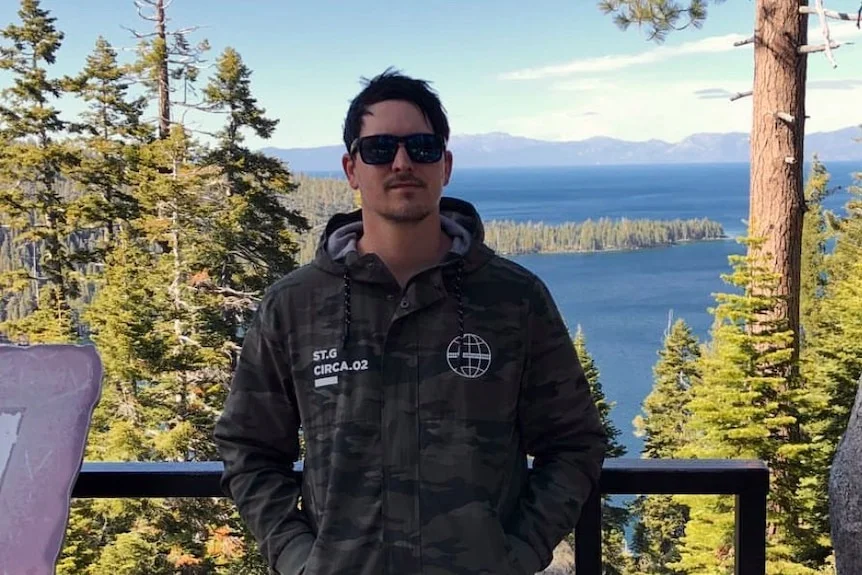 A man standing in front a picturesque lake