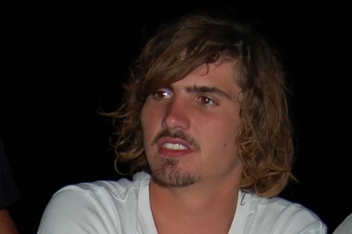 A man in a white shirt poses for a photo at night