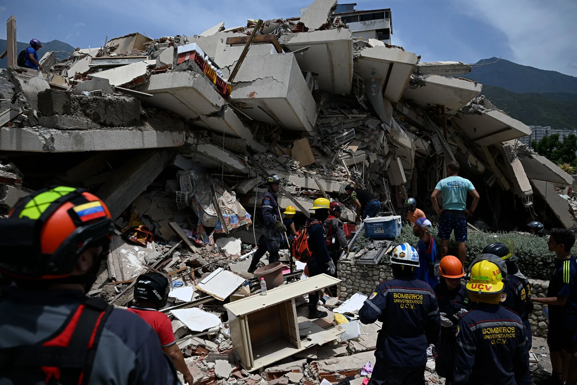 Firefighters and rescuers stand next to a collapsed building following a twin earthquake in Los Corales