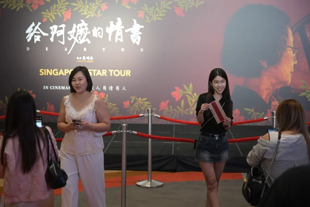 People pose in front of a billboard of “Dear You” during the film’s premiere in Singapore on June 17. Photo: Xinhua