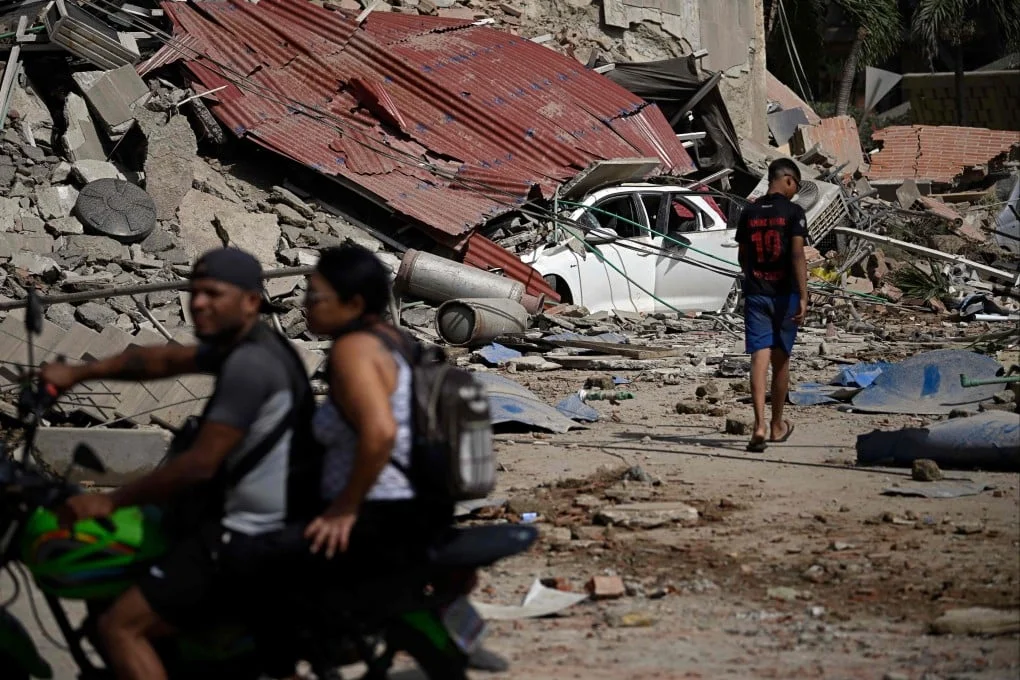 People walk and ride past collapsed structures and debris following an earthquake in Catia La Mar, Venezuela, on Wednesday. Photo: AFP