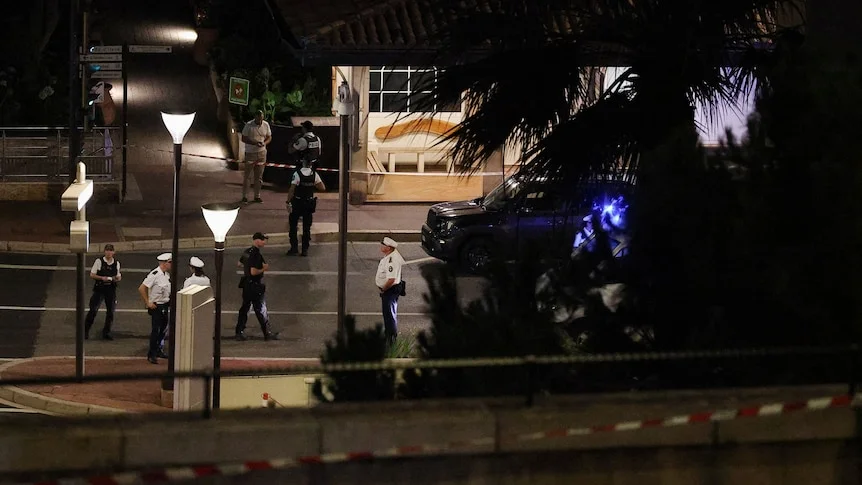 Police stand around a street at night. 