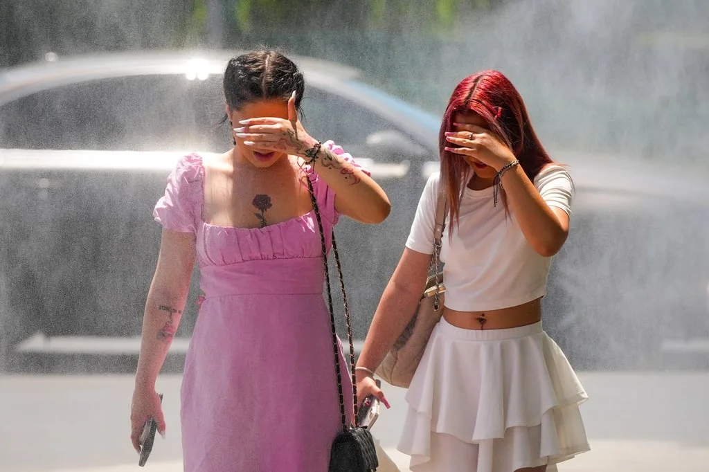 People walk by a water mist machine in Romania’s city of Bucharest. The machine was installed by officials to help with coping in the heat. Photo: AP People walk by a water mist machine in Romania’s city of Bucharest. The machine was installed by officials to help with coping in the heat. Photo: AP